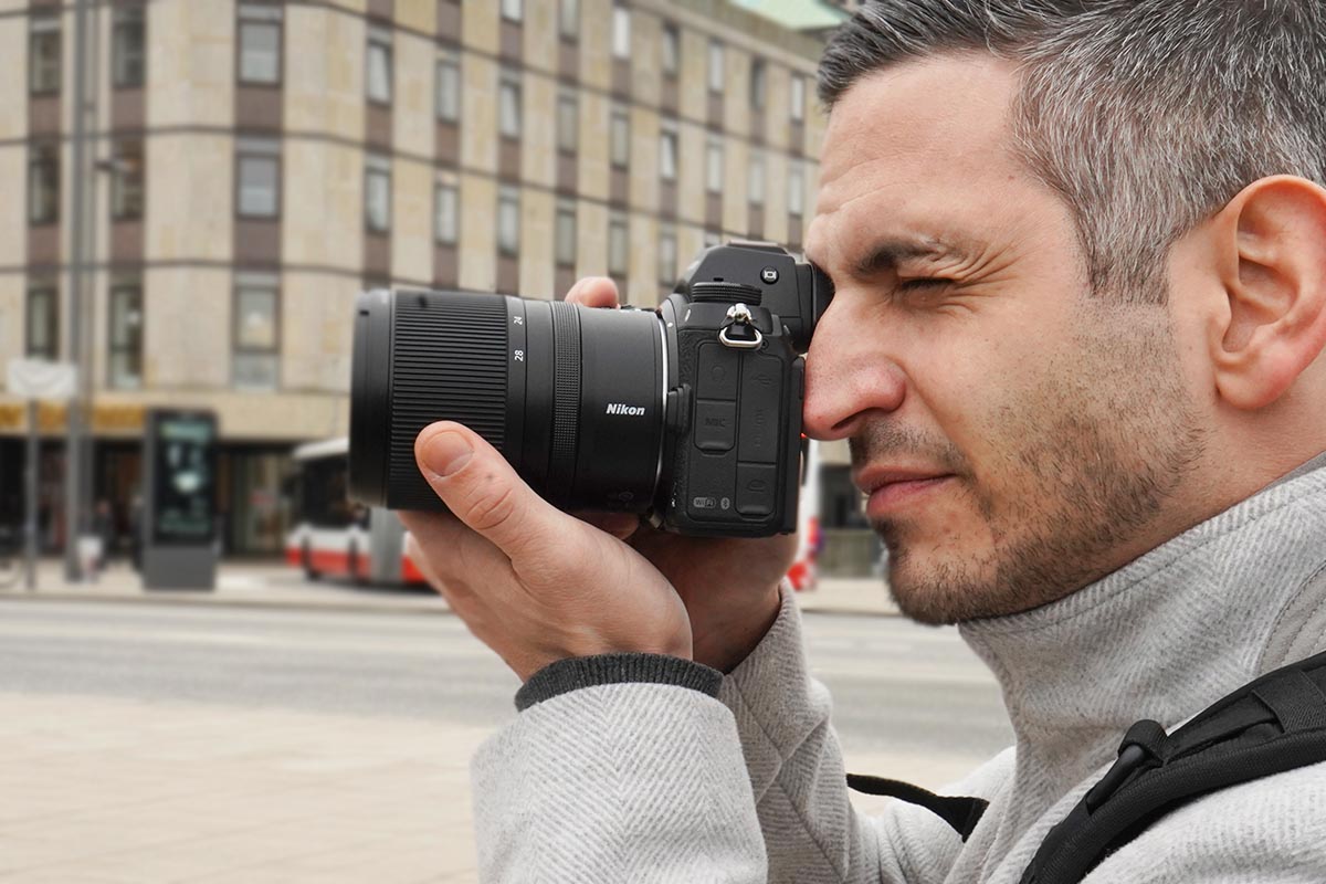 In der Hand gehaltene Kamera mit dem Objektiv Nikkor Z 17-28 mm von Nikon unter freiem Himmel.