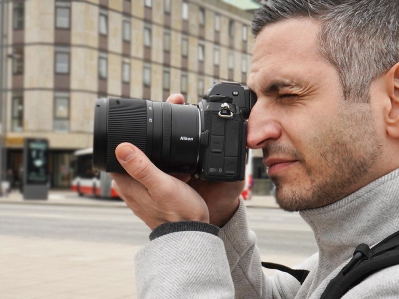 In der Hand gehaltene Kamera mit dem Objektiv Nikkor Z 17-28 mm von Nikon unter freiem Himmel.