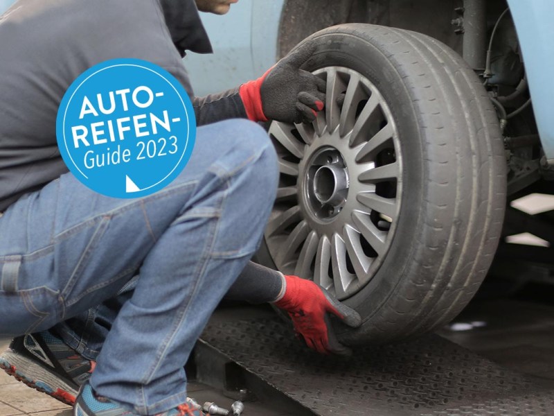 Person wechselt einen Reifen an einem Auto