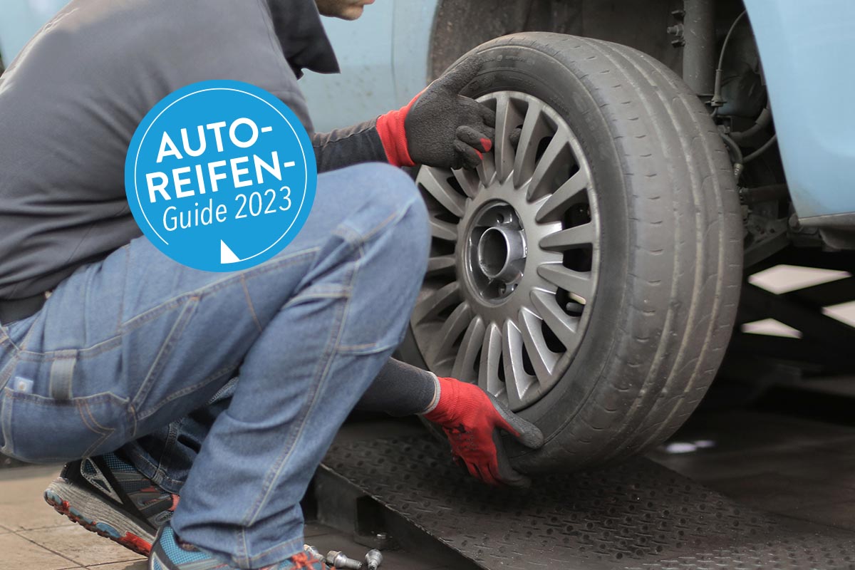 Person wechselt einen Reifen an einem Auto