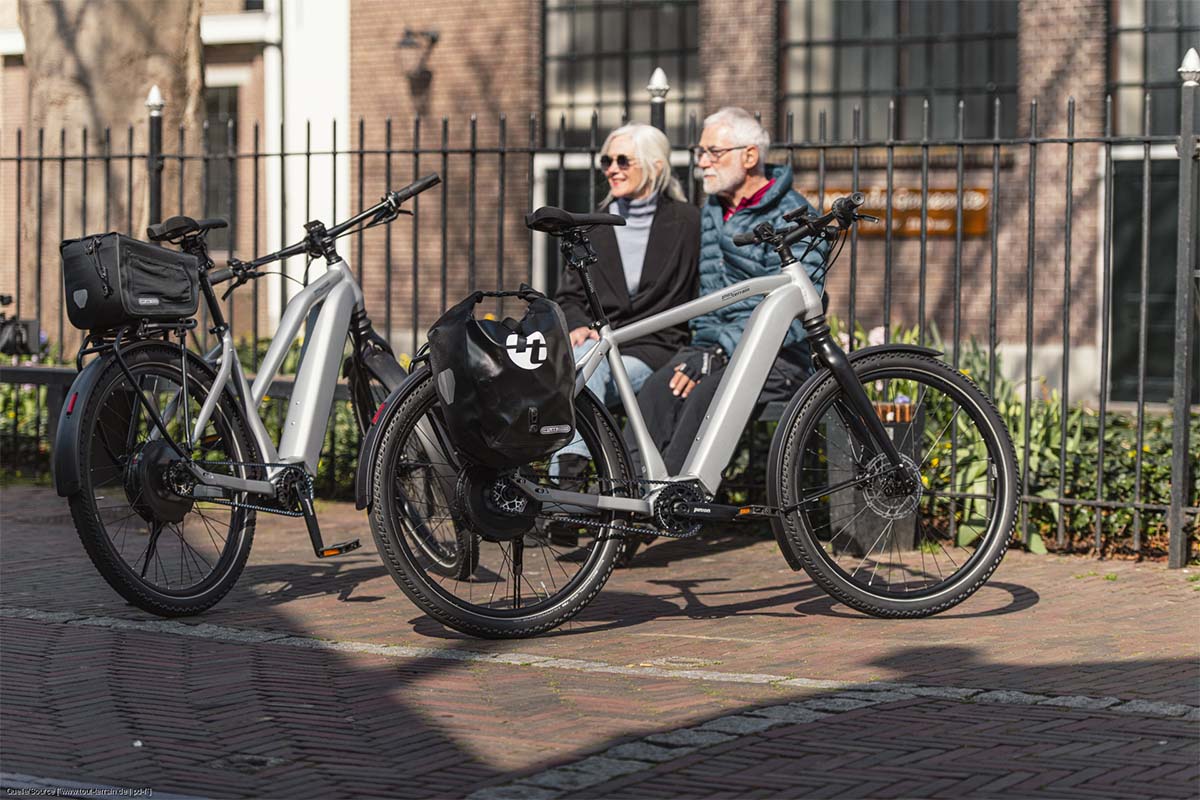 Zwei ältere Menschen sitzen auf einer Bank, vor ihnen stehen ihre E-Bikes