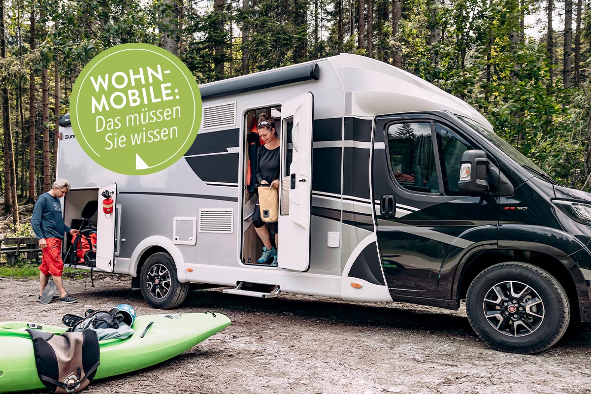 Zwei Personen an einem Wohnmobil in einem Wald