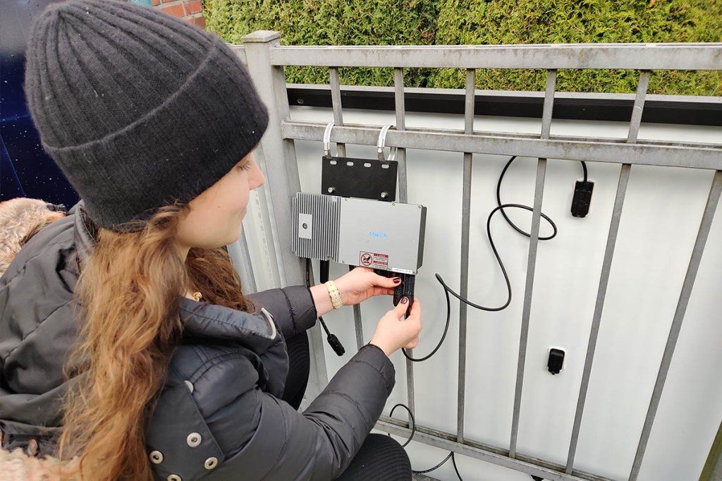 Die IMTEST-Redakteurin schließt das Solarpanel des Balkonkraftwerks an den Wechselrichter an.