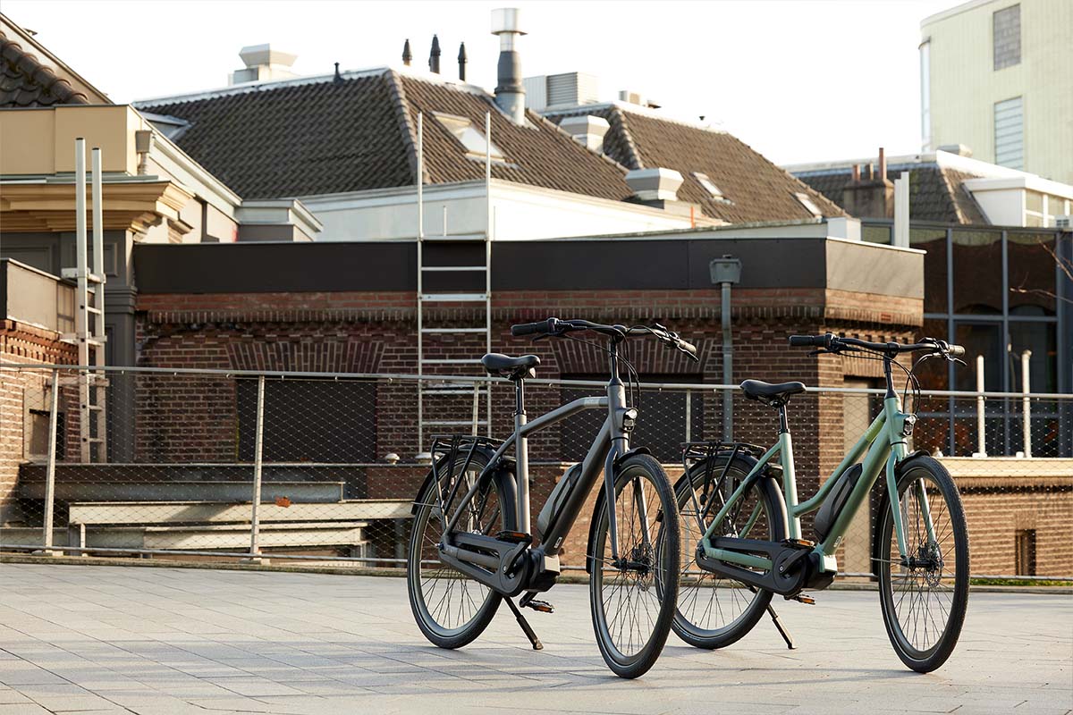 Zwei E-bikes stehen nebeneinander auf einem Platz, städtischer Hintergrund
