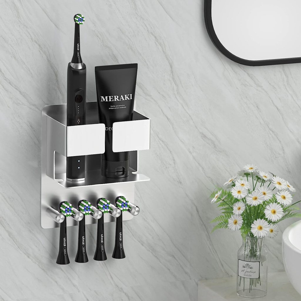 Silberne halterung mit schwarzer elektrischer Zahnbürste oben, schwarzer Zahnpastatube daneben und eingehängten schwarzen Bürstenköpfen unten eingehängt vor weiß marmorierter Wand