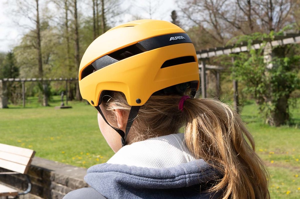 Nahaufnahme Frau mit Fahrradfhelm im Park von hinten