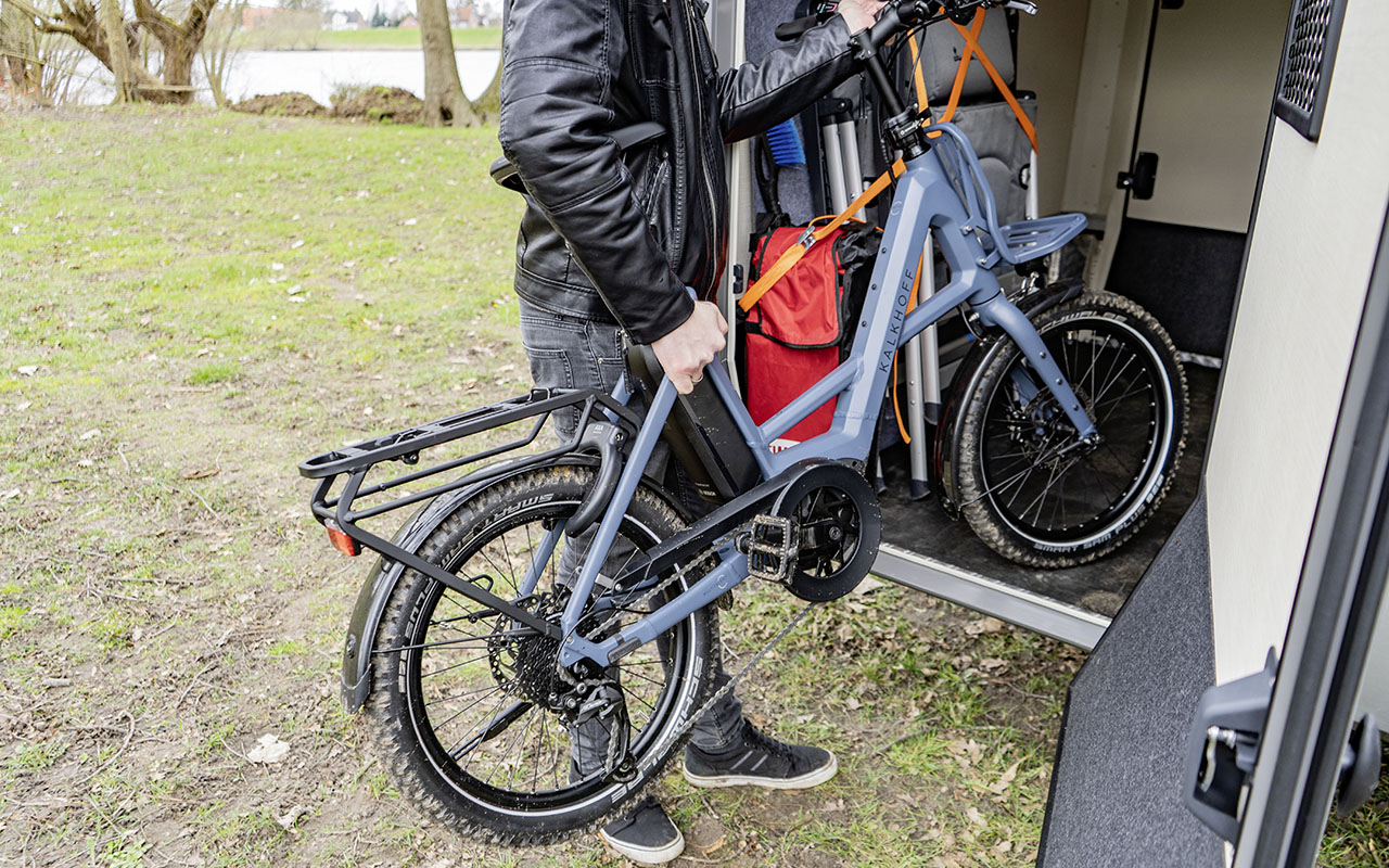 Ein E-Bike wird in einer Heckgarage bei einem Wohnmobil gehoben.