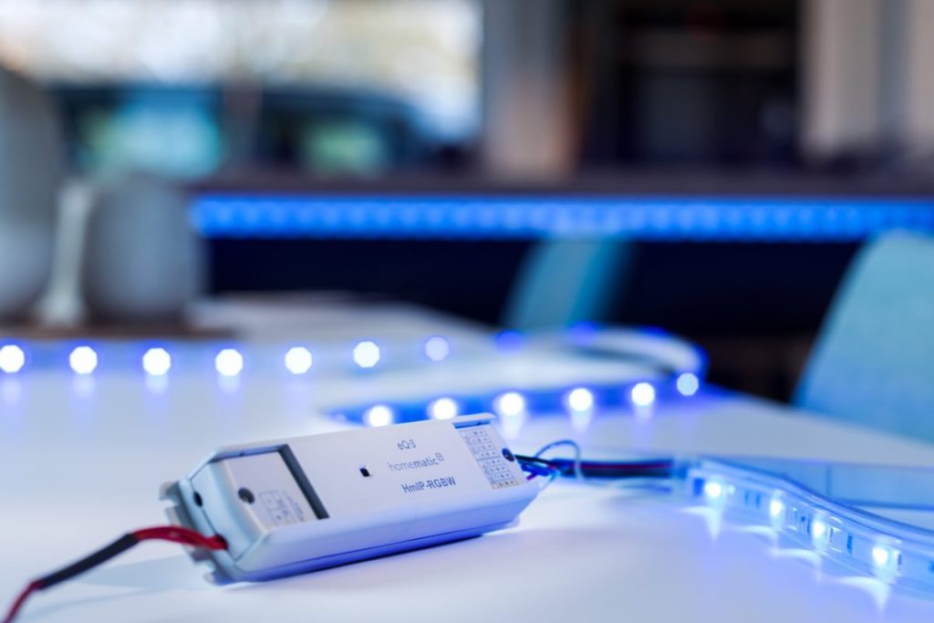 Ein LED-Controller liegt auf einem Tisch und ist an einen blau leuchtenden LED-Stripe angeschlossen.
