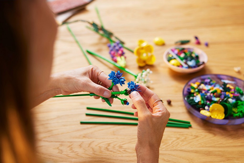 Eine Frau baut das Lego-Set Wildblumen.