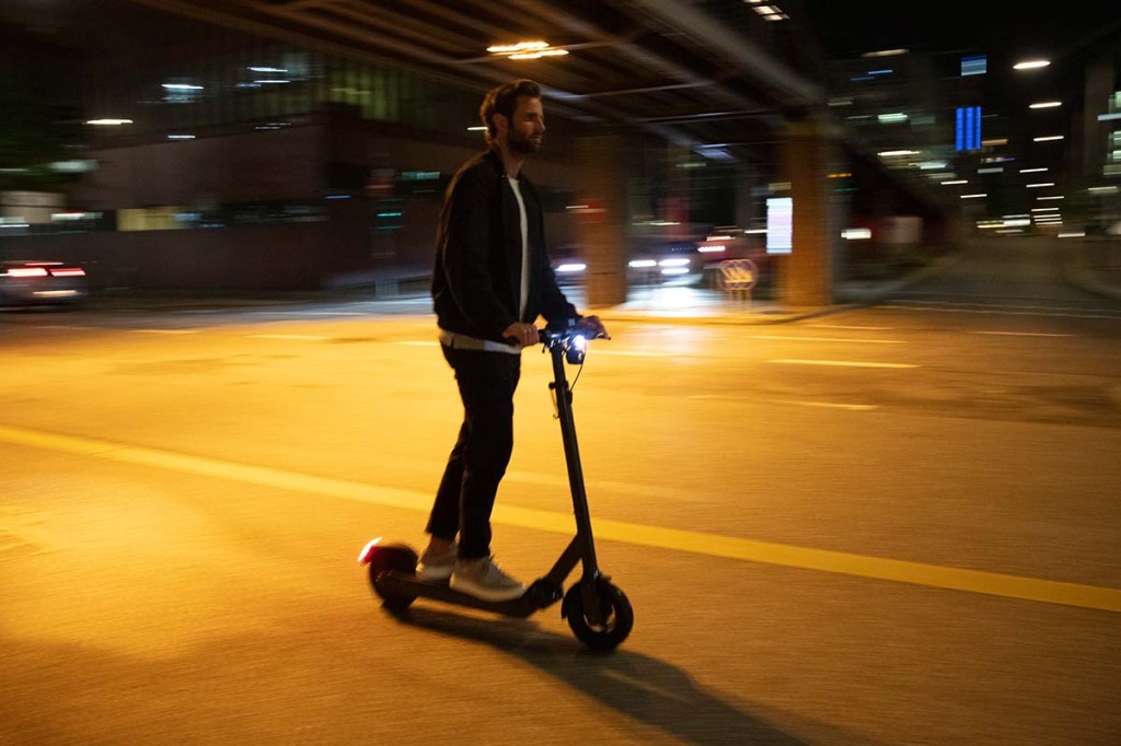 Mann fährt mit E-Scooter Egret Pro durch die nächtliche Stadt