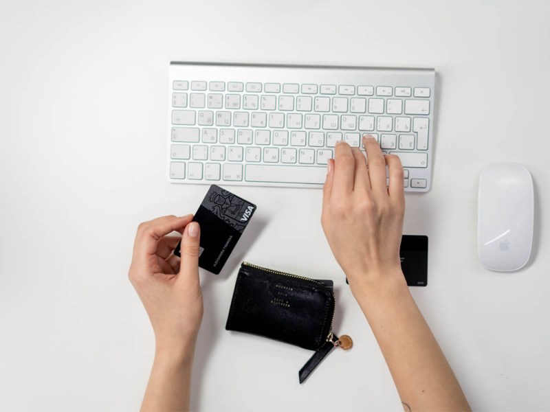 Ein Mensch mit einer Kreditkarte tippt auf einer Tastatur.