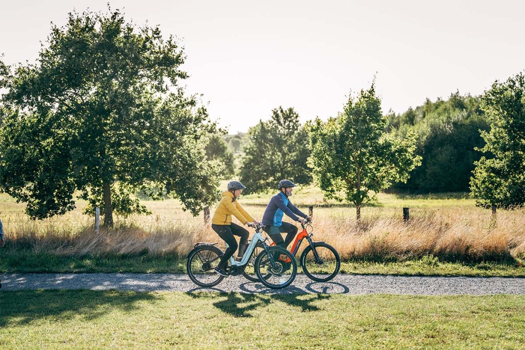 Zwei Menschen fahren mit dem E-Bike durch die Natur