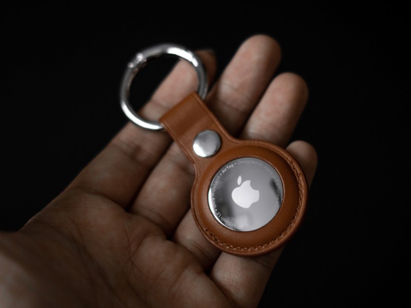 Eine Hand hält einen AirTag von Apple.