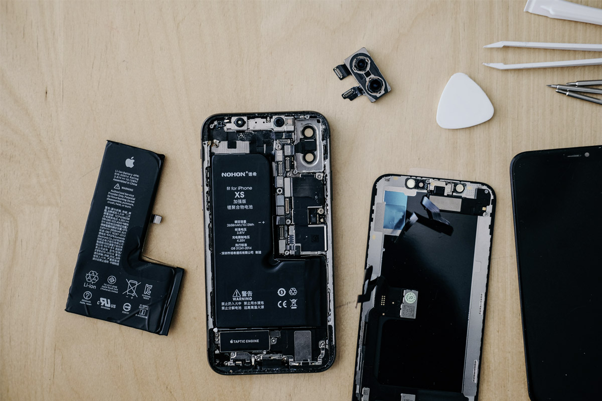 Ein iPhone wird repariert, auf einer Holzplatte liegend.