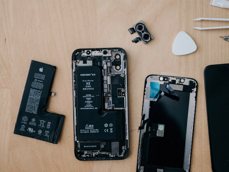 Ein iPhone wird repariert, auf einer Holzplatte liegend.