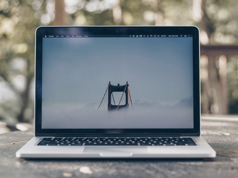 Ein MacBook steht auf einem Tisch im Freien.