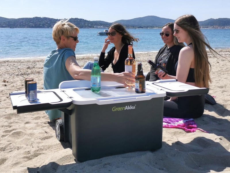 Vier Frauen an einem Strand sitzend mit einer Kühlbox von GreenAkku.
