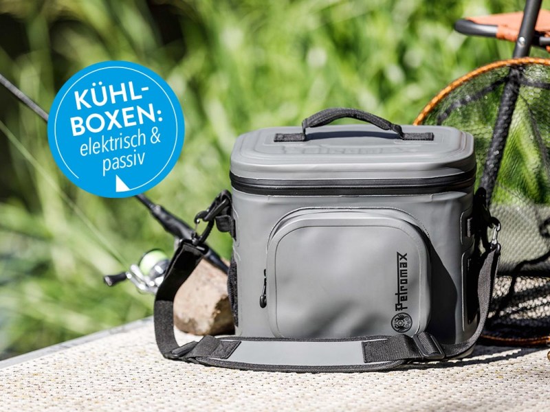 Kühlbox neben einer Angelrute unter freiem Himmel.