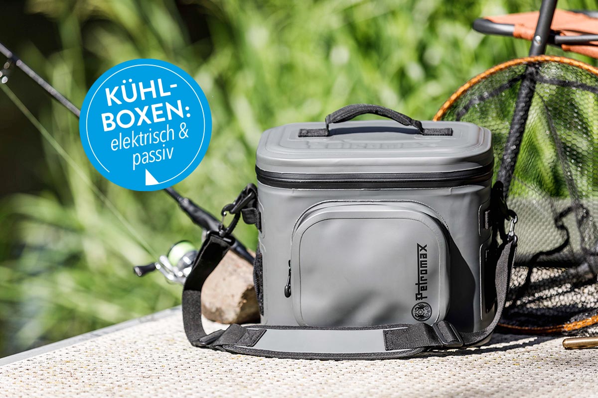 Kühlbox neben einer Angelrute unter freiem Himmel.