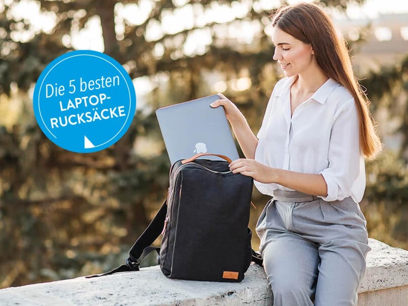 Frau mit einem Laptop-Rucksack auf einer Steinmauer sitzend.
