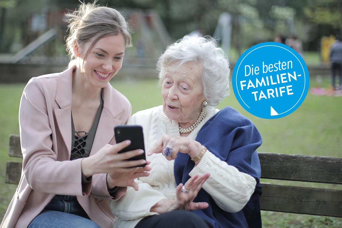 Zwei Frauen auf einer Parkbank mit einem Smartphone in der Hand.