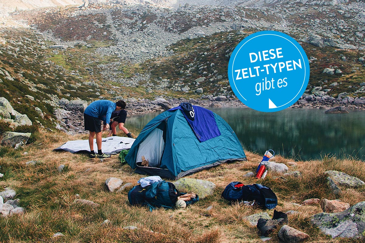 Personen stellen ihr Zelt an einem See auf.