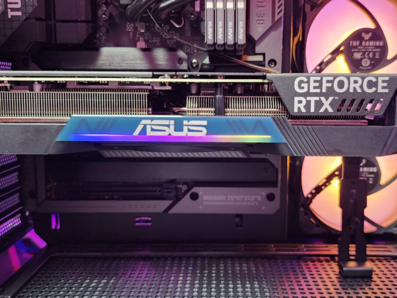 Eine Grafikkarte im PC eingebaut, im Hintergrund bunte Lüfter