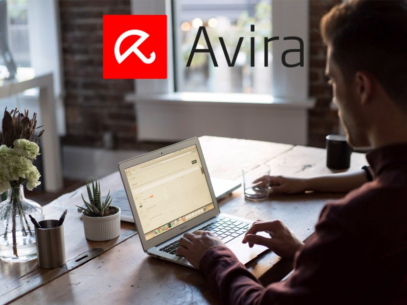 Ein Mann tippt an einem Laptop, der vor ihm auf dem Tisch steht, dazu das Avira Logo.