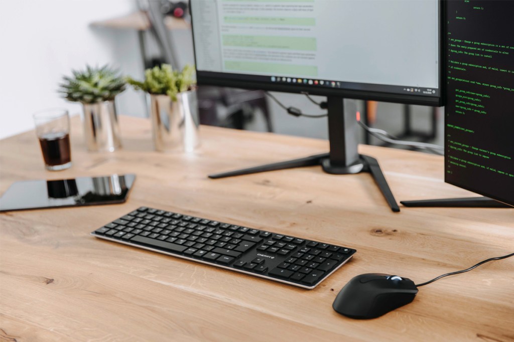 Die Cherry-Tastatur liegt vor einem Monitor auf einem Schreibtisch.