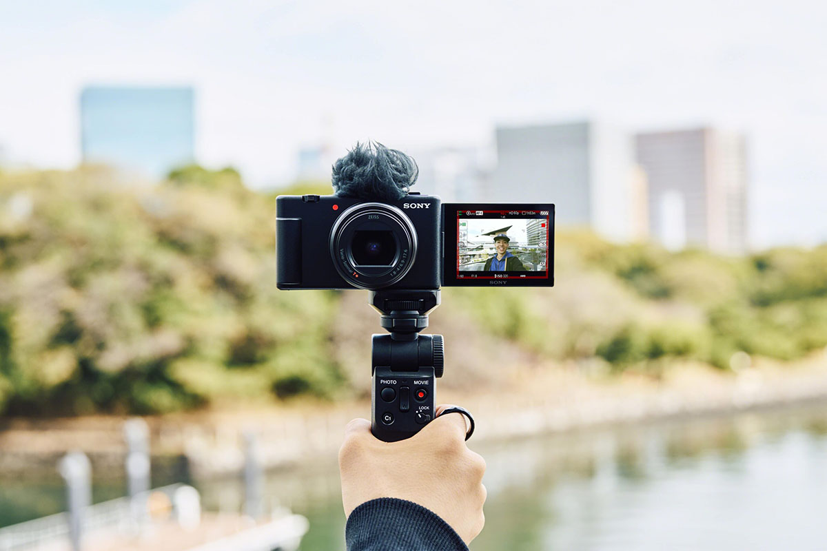 Sony ZV-1 II auf einem Hand-Gimbal montiert für eine Selfie-Aufnahme vor einem Stadtpark.