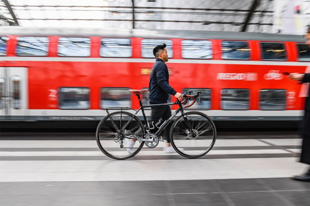 Ein Mann läuft mit einem Fahrrad am Bahnsteig entlang.