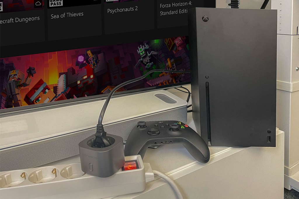 Eine Xbox mit Kontroller und Fernseher. Sie ist mit einem EcoFlow-Smart-Plug in die Steckerleiste gesteckt.