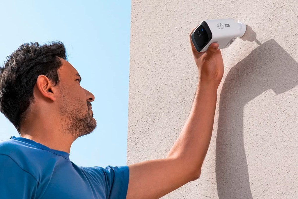 Ein Mann installiert die Sicherheitskamera an einer Hauswand.