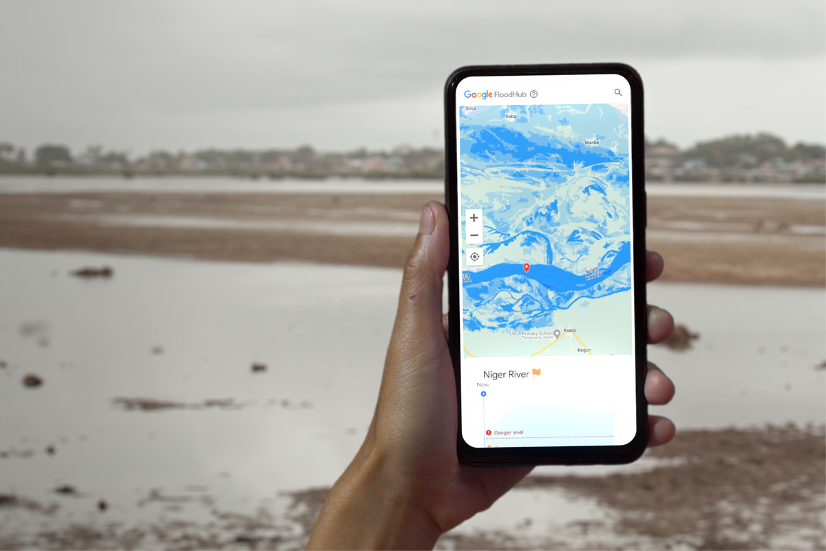 Die FloodHub-Anwendung auf einem Smartphone, im Hintergrund eine Flusslandschaft.