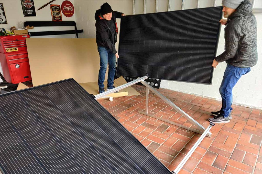 Zwei Männer heben ein GreenAkku-Solarpanel auf die vormontierte Halterung.