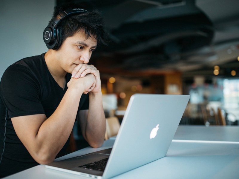 Ein Mann sitzt vor einem Laptop mit einem erstaunten Gesichtsausdruck.