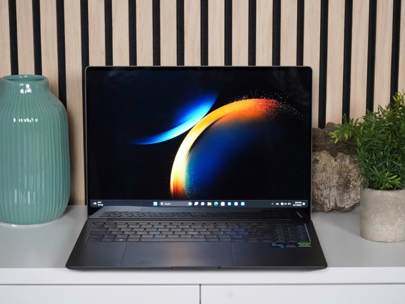 Das Samsung Galaxy Book3 auf einem Sideboard zwischen einer Vase und einer kleine Zimmerpflanze.