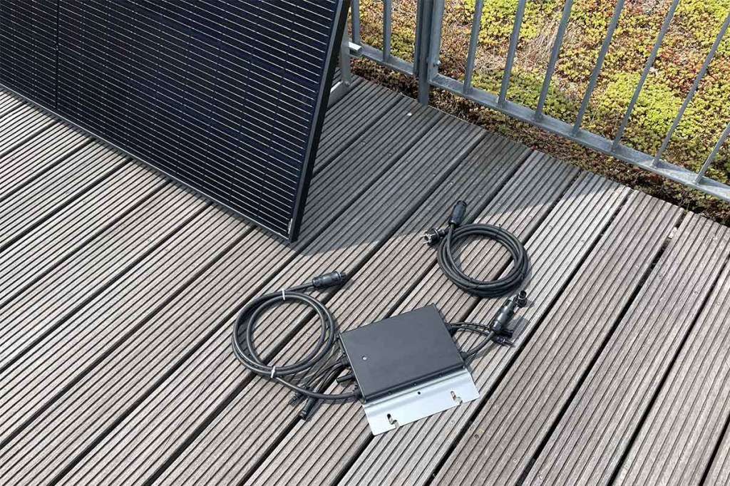 Der Hoymiles-Wechselrichter mit Kabeln vor dem Solarpanel.