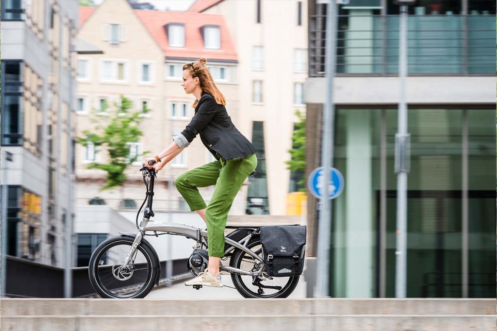Frau fährt mit Falt-E-Bike durch die Stadt