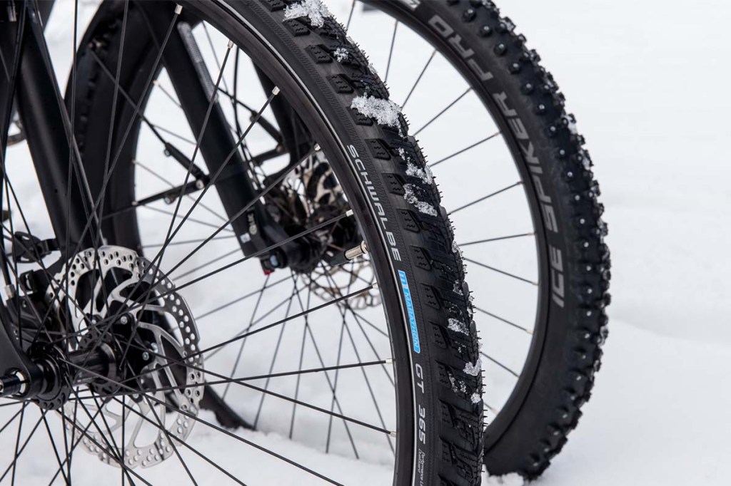 Nahaufnahme: Zwei Fahrrad-Vorderräder dicht beieinander, im HIntergrund sieht man Schnee