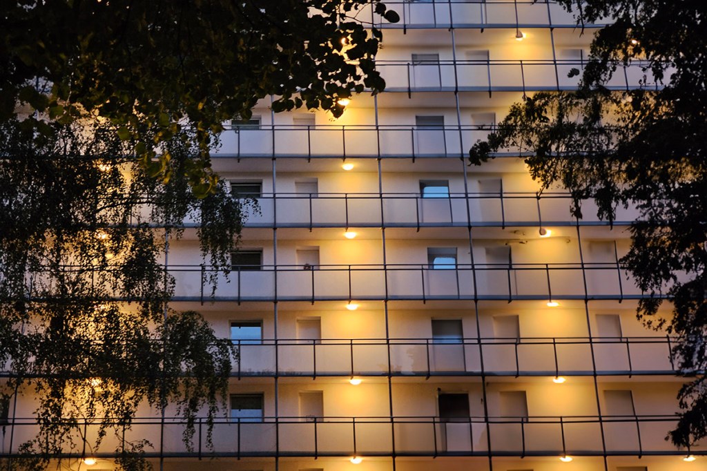 Nachtaufnahme einer Wohnungsfassade mit Beleuchtung in den EtagenGängen