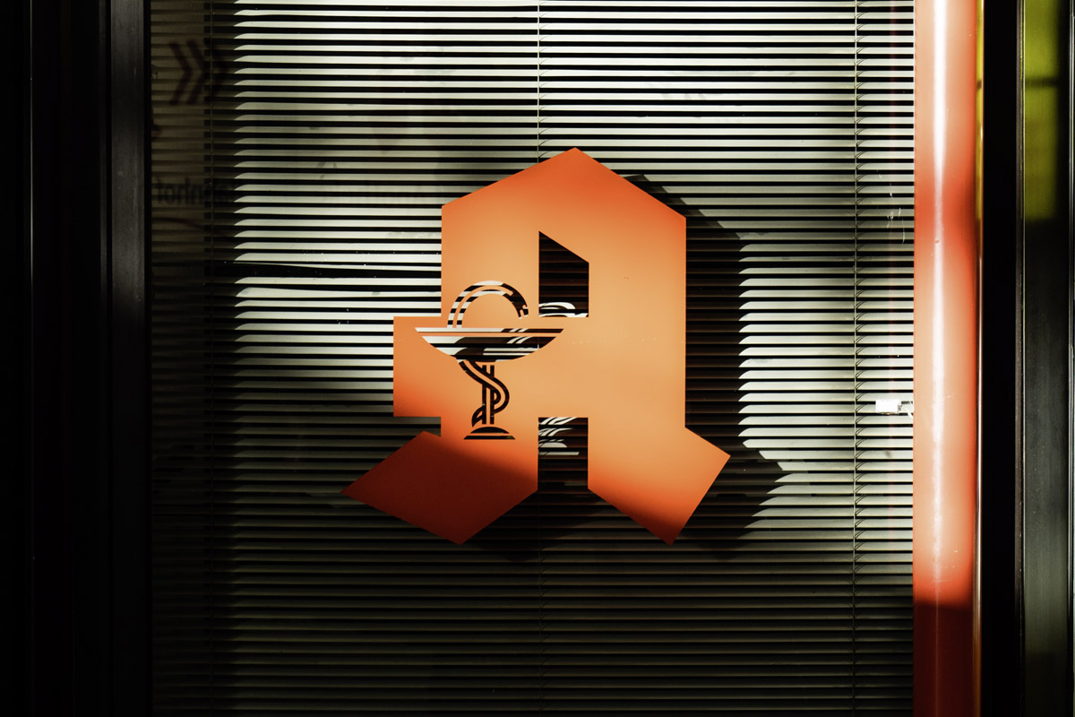 Ein Apothekensymbol vor einem verschlossenen Fenster.