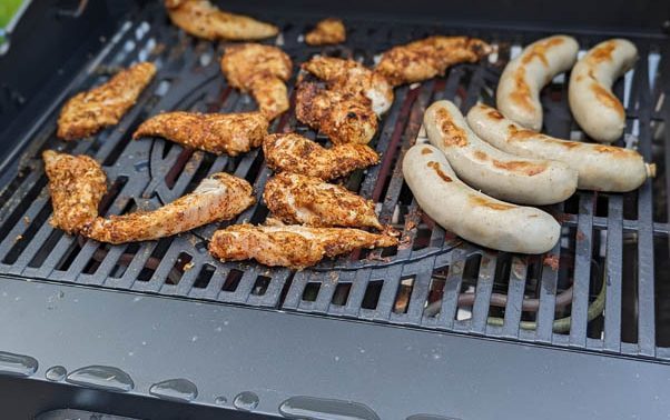 Hähchenfilet und Würste auf dem Rost eines Elektrogrills