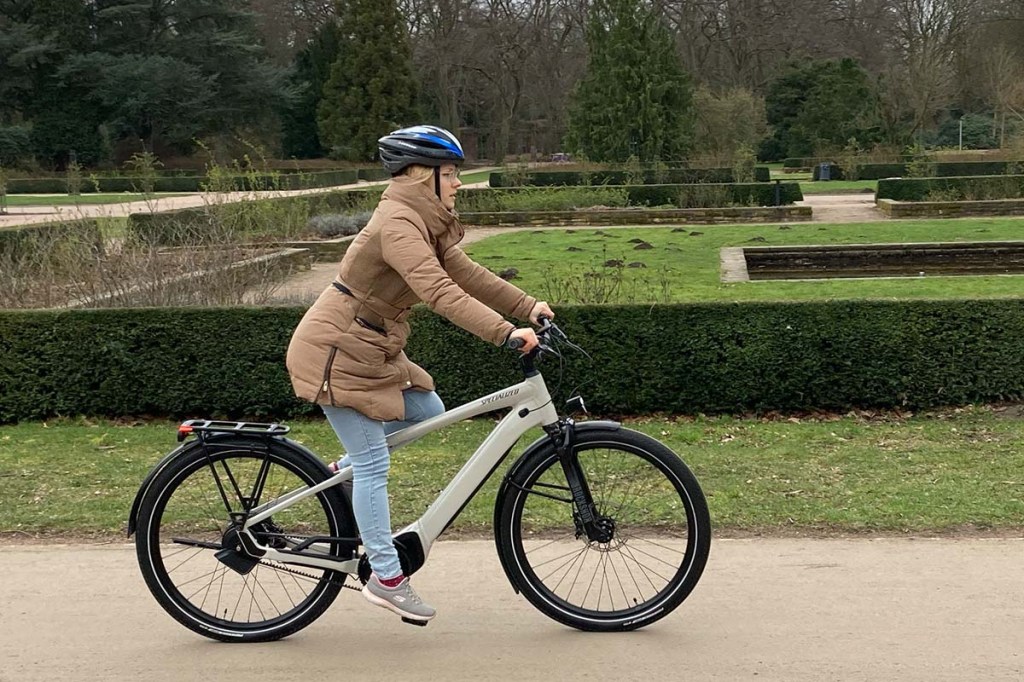 Frau fährt mit E-Bike durch einen Park
