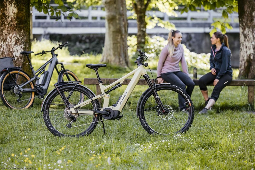 Zwei Frauen sitzen im Park auf einer Bank, vor ihnen stehen ihre Fahrräder