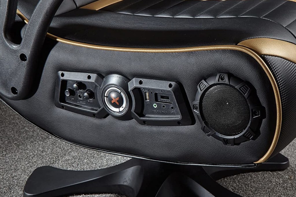 Detailed shot of a black and gold gaming chair from the side with various controls and connections