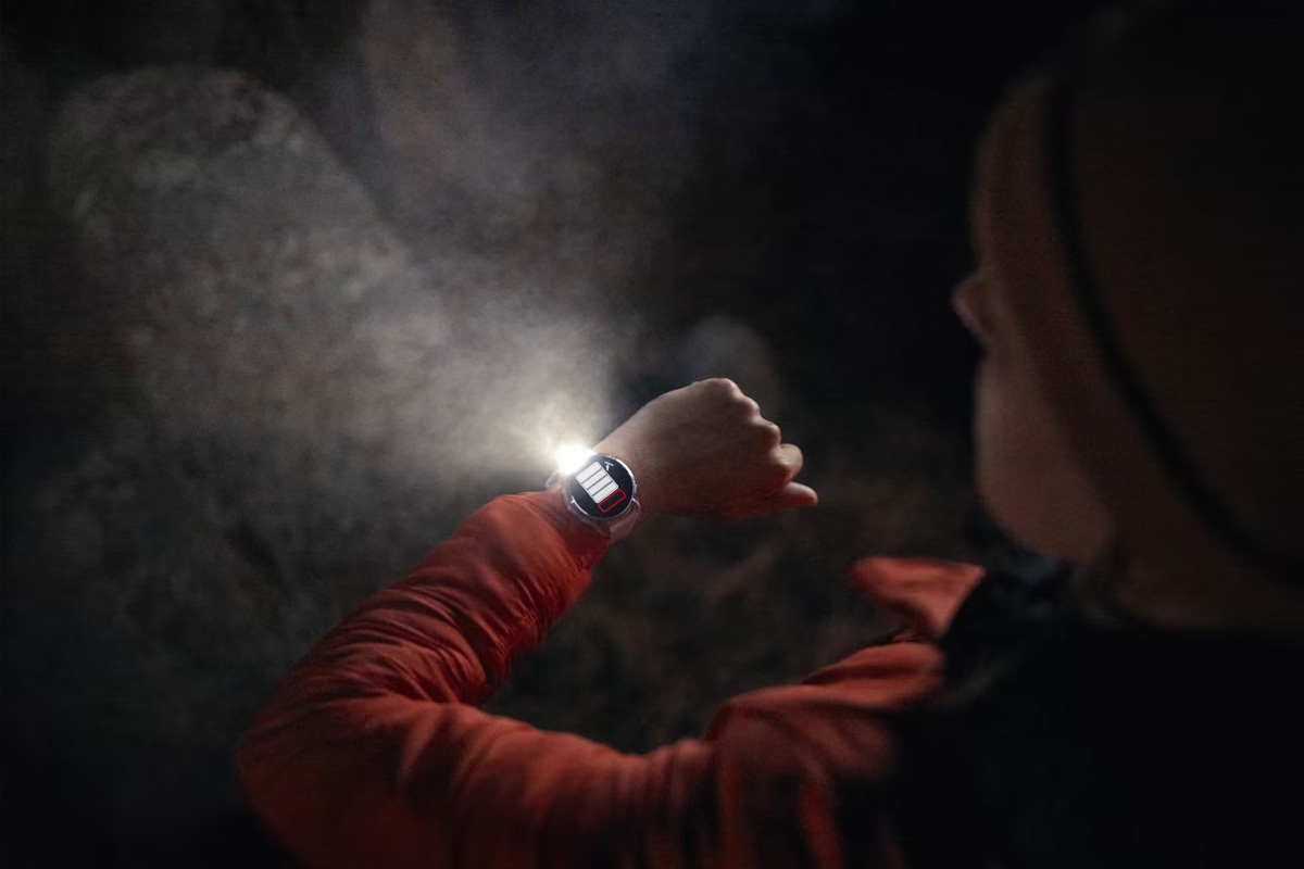 Eine Person schaut im Dunkeln auf die Garmin Smartwatch, die auch eine Taschenlampe integriert hat.