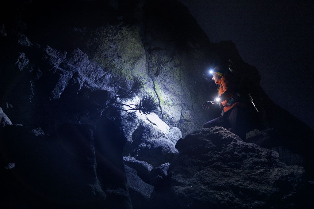 Eine Person geht durch eine dunkle Höhle mit LIcht von einer Stirnlampe und einer Garmin-Smartwatch.