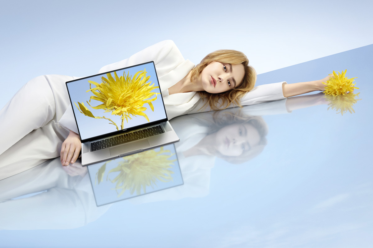 Eine Frau liegt neben einem Laptop von Huawei.