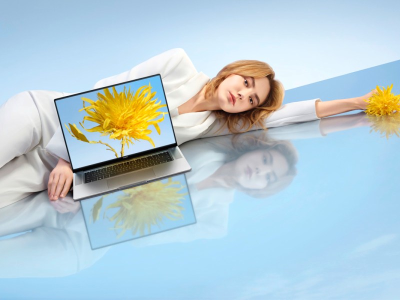 Eine Frau liegt neben einem Laptop von Huawei.